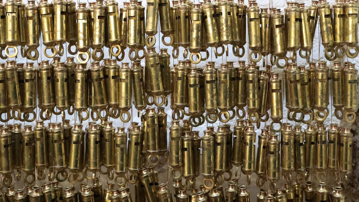 Rows of brass whistles hanging in factory.
