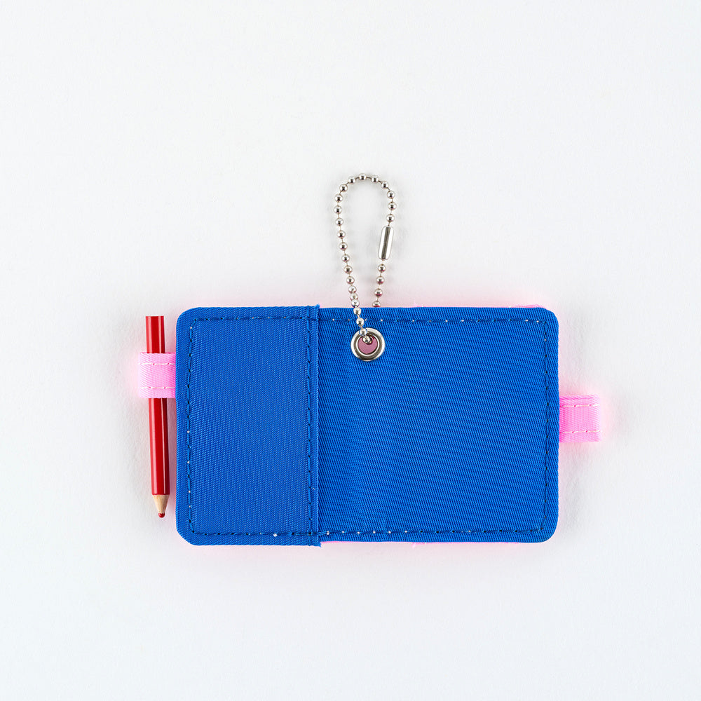 Open small blue notebook keychain with a silver ball chain and a pink loop holding a red pencil, shown on a plain white background.