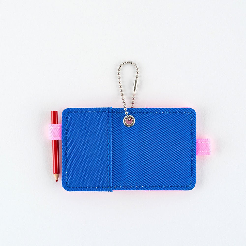 Open small blue notebook keychain with a silver ball chain and a pink loop holding a red pencil, shown on a plain white background.