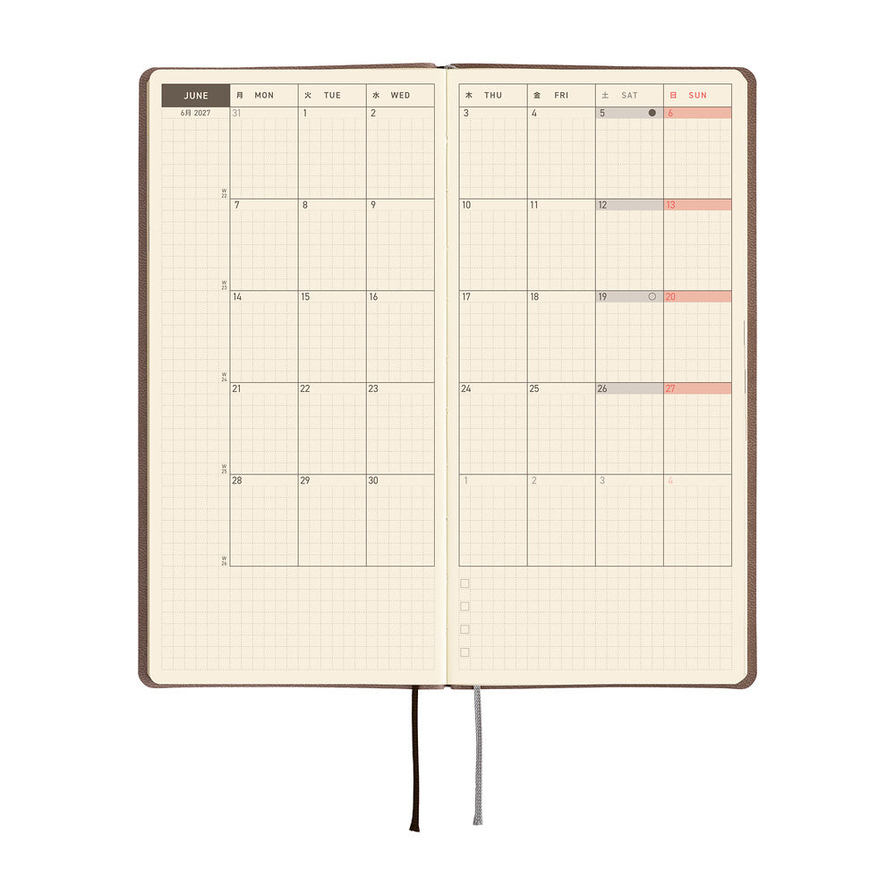 An open planner or journal showing a monthly calendar spread on warm cream grid pages.