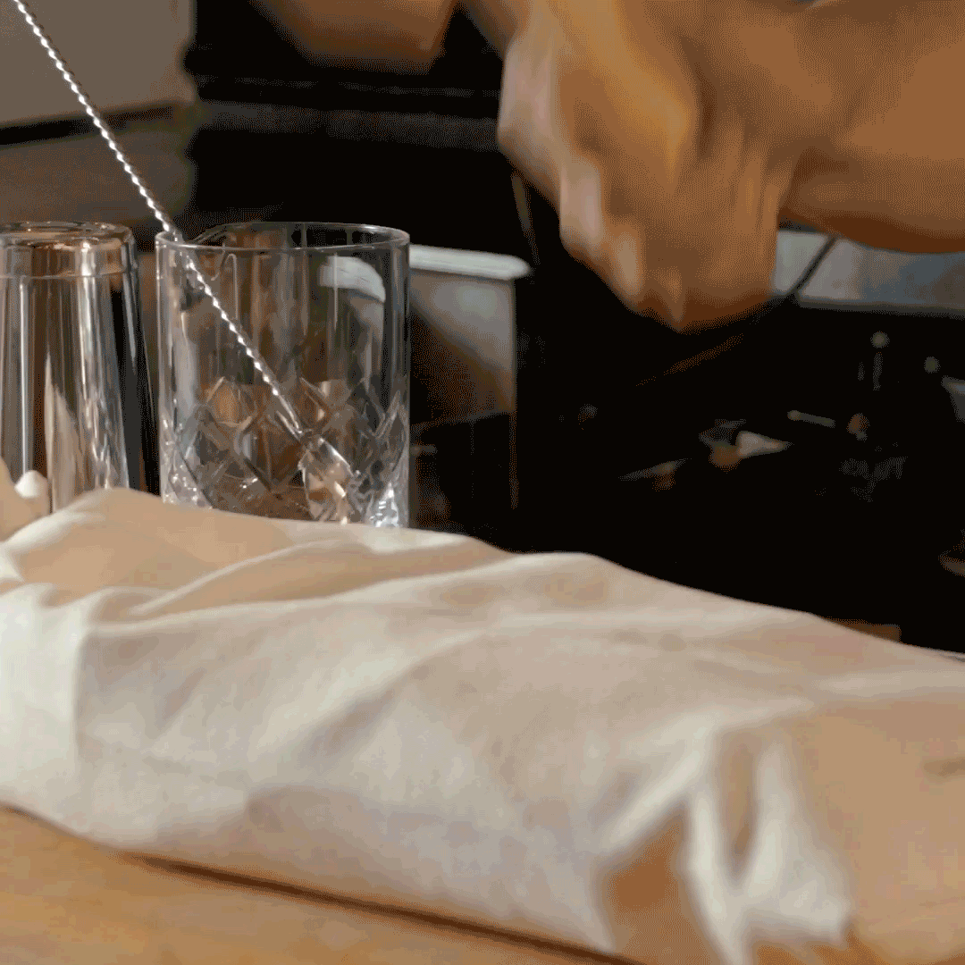 Gif of hand using wooden mallet to crush ice in bag on bar top
