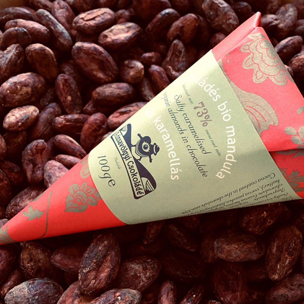 Bag of salty caramelized almonds on pile of chocolate-covered nuts.