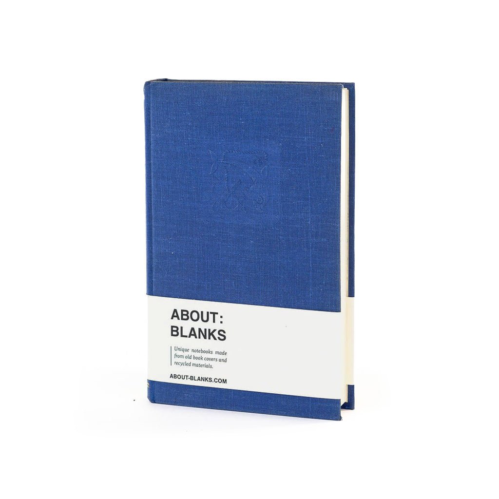 A blue linen-covered notebook or journal standing upright on a white background, with a white paper band around the lower middle that reads 'ABOUT: BLANKS'.