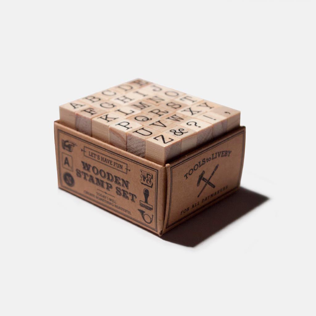 A wooden stamp set in a cardboard box on a white background.