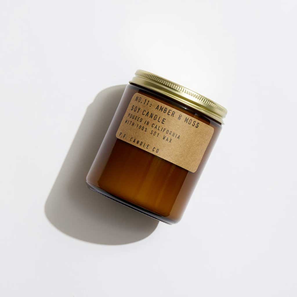 Scented candle with a gold lid and brown label on a white background