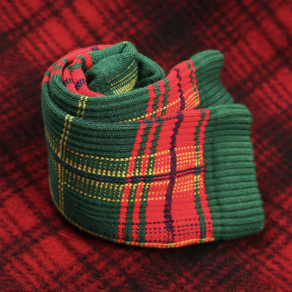Rolled up sock with red and green plaid pattern on plaid fabric.