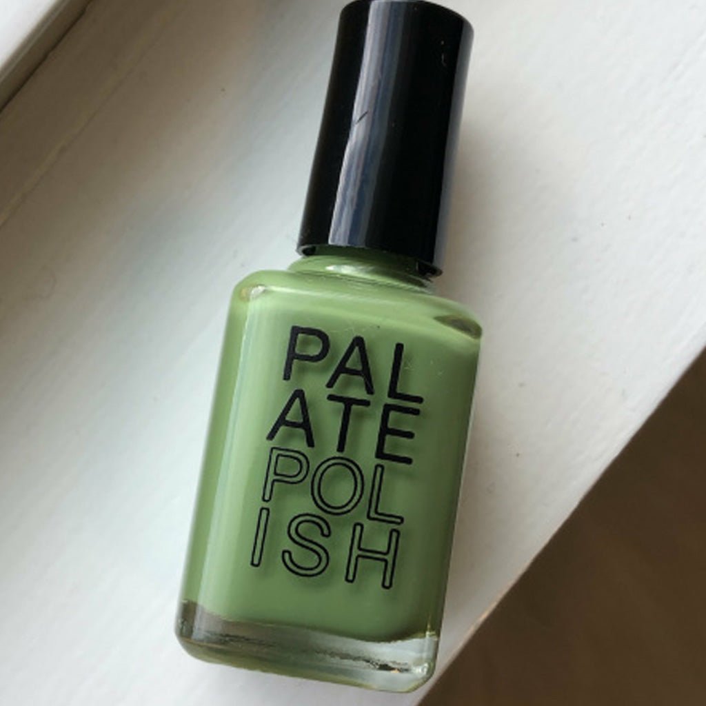 Bottle of artichoke green nail polish on white surface