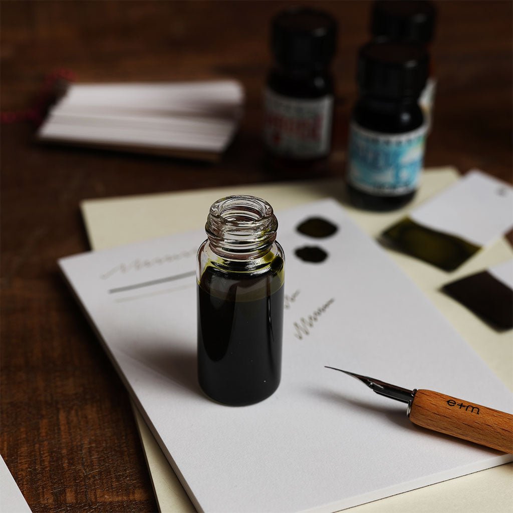 Ink bottle with a writing implement on a wooden surface
