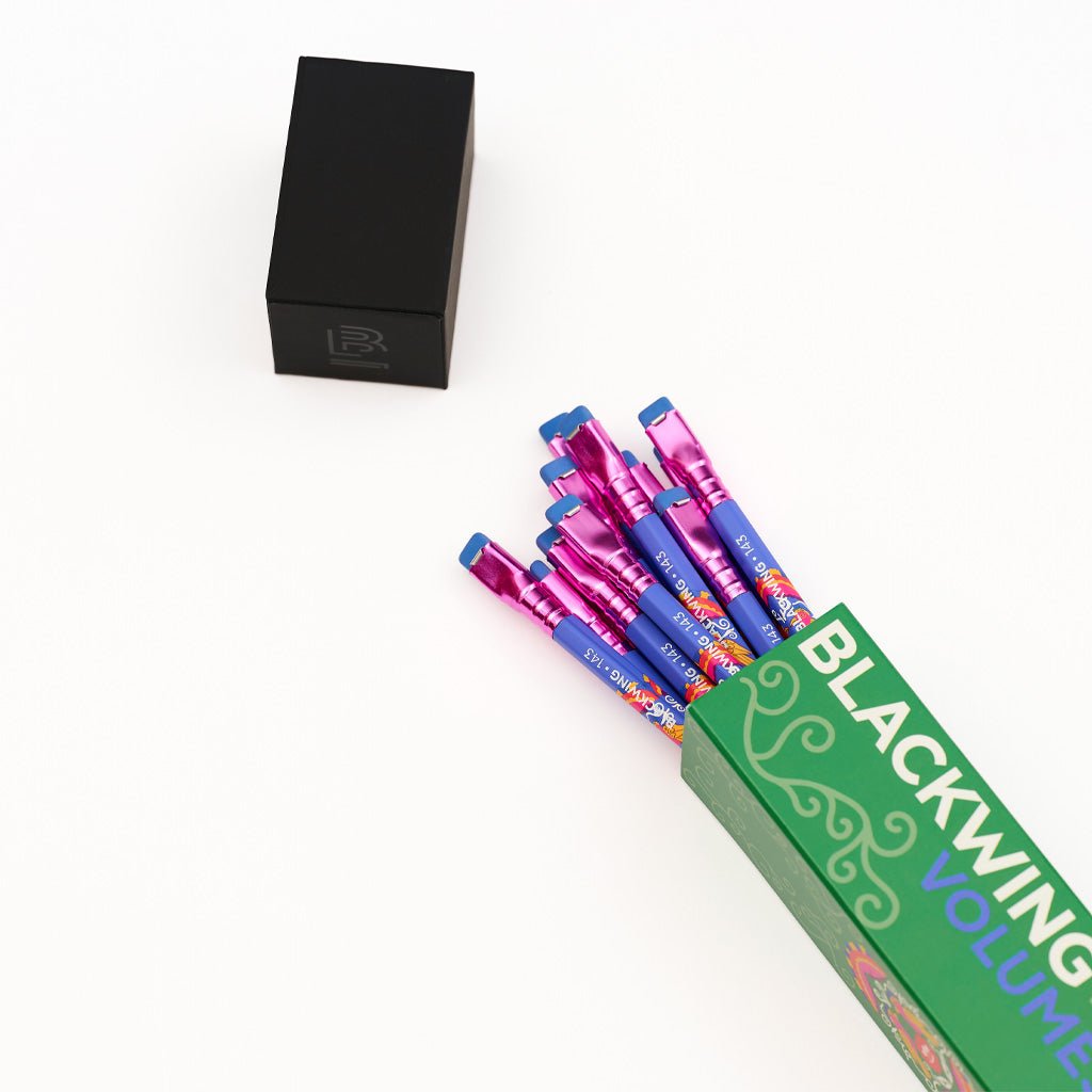 Open box of pencils on white surface next to box cap.