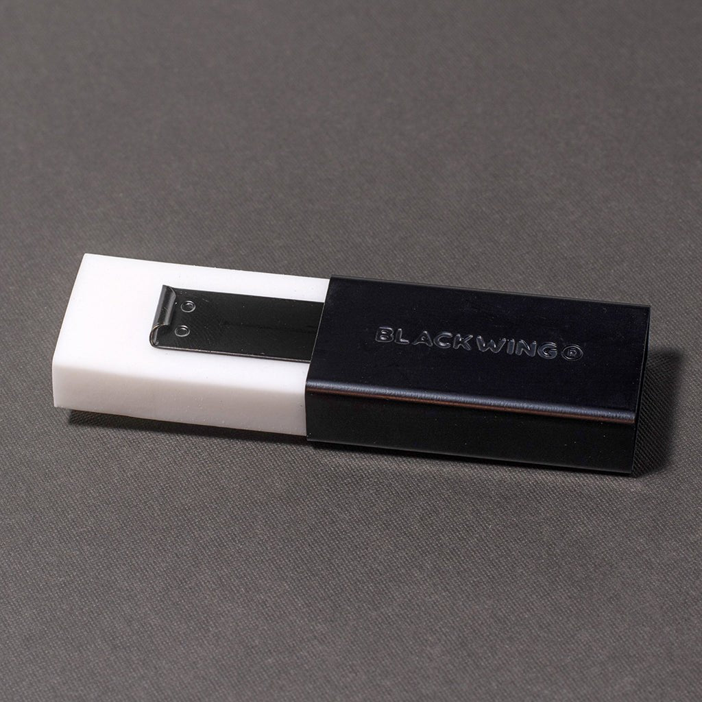 White eraser pulled out of black eraser holder with Blackwing branding on gray surface