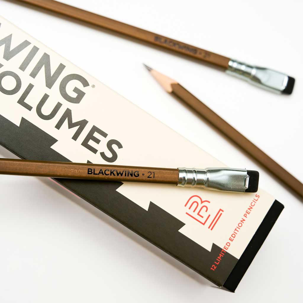A close-up photo showing the blackwing logo imprinted in black on brown Volumes 21 pencil that has a silver ferrule and black eraser.