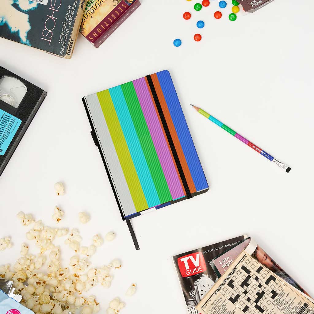 Blackwing 343 notebook with color bar cover and pencil surrounded by popcorn and media on white background