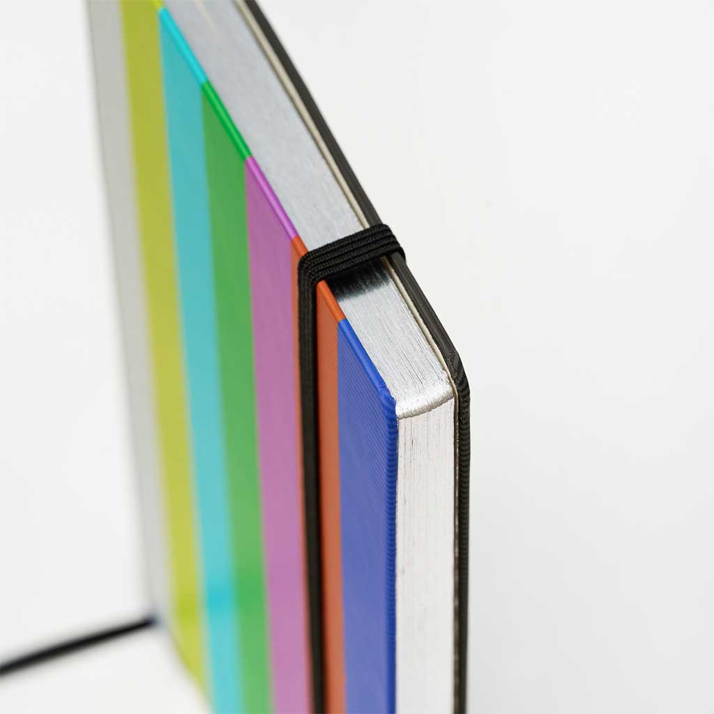 Closed Blackwing 343 notebook with color bar cover and silver gilded edged pages on white background