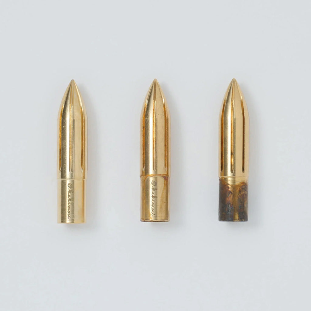 Three brass nibs in various rusting stages on gray background