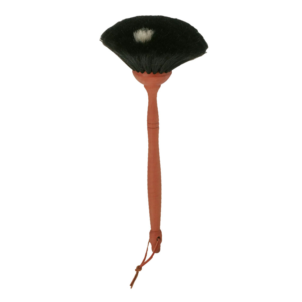 A goat hair dust brush with a pear wood handle and leather loop and black bristles on white background