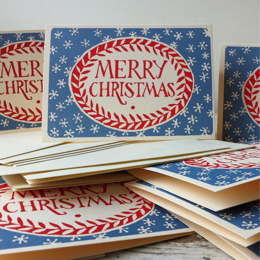 Red and blue Merry Christmas cards standing upright on top of other cards and envelopes.