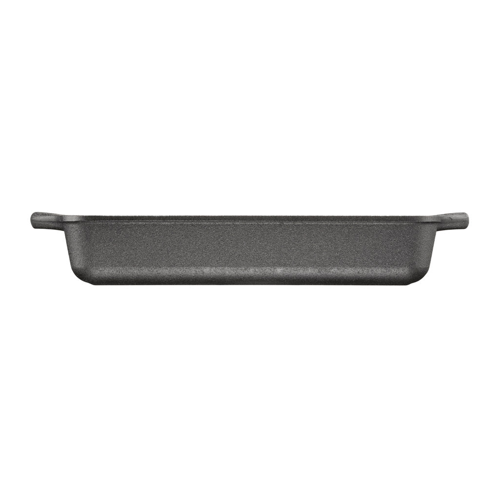 Side profile of black rectangular cast iron baking dish with handles on a white background