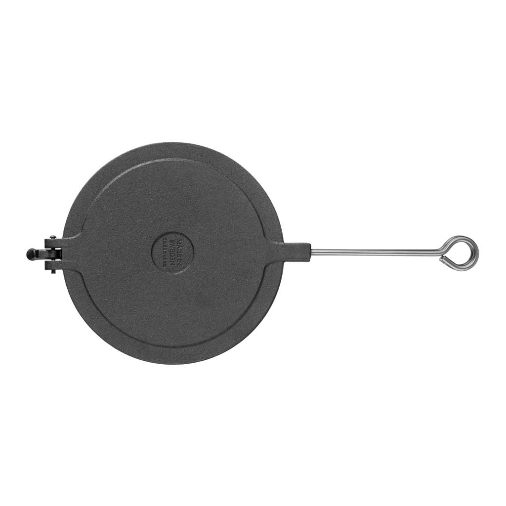 Black cast iron waffle iron closed with aluminum handle on white background