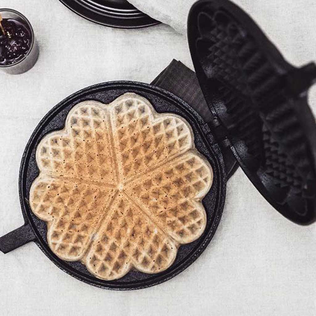 Waffle iron with a freshly made waffle on a light surface