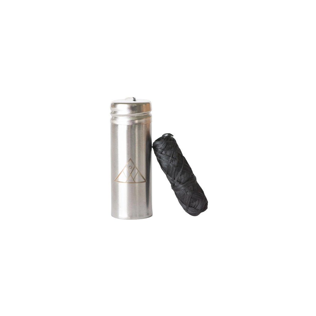 Stainless steel holder next to spool of charcoal dental floss on white background