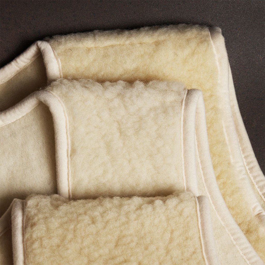 Close-up showing slight variations in shade between three natural woolen vests.