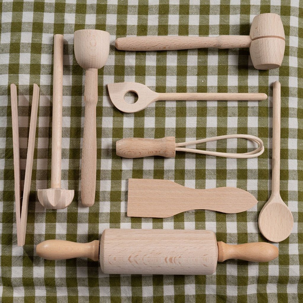 Set of wooden kitchen utensils on a green and white checkered tablecloth