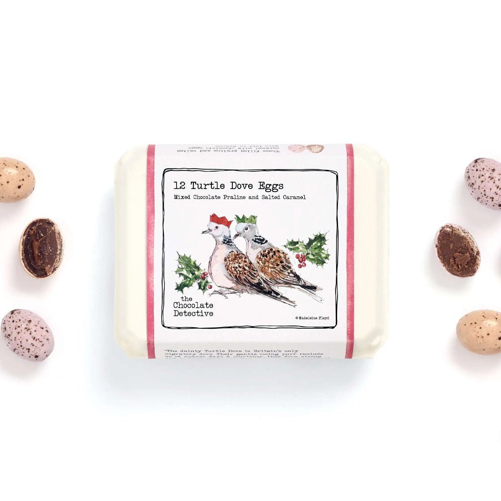 Front of chocolate egg carton next to speckled eggs.