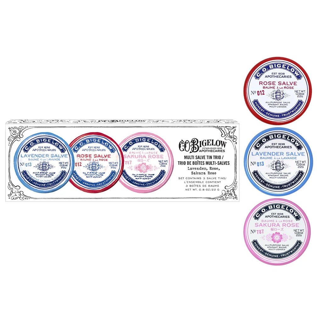 Three lip salve tins next to box packaging.