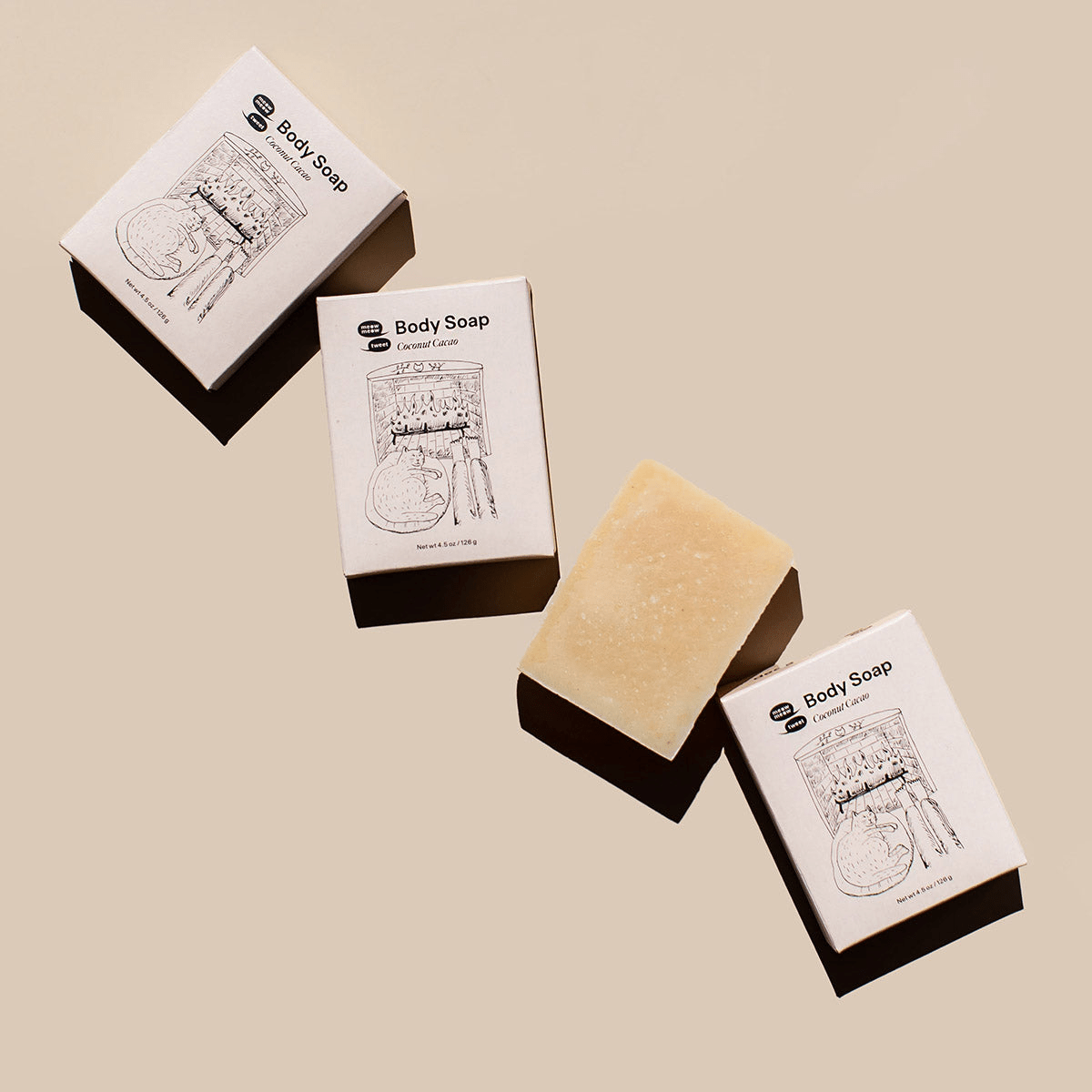 Three bars of body soap with their packaging on a beige background