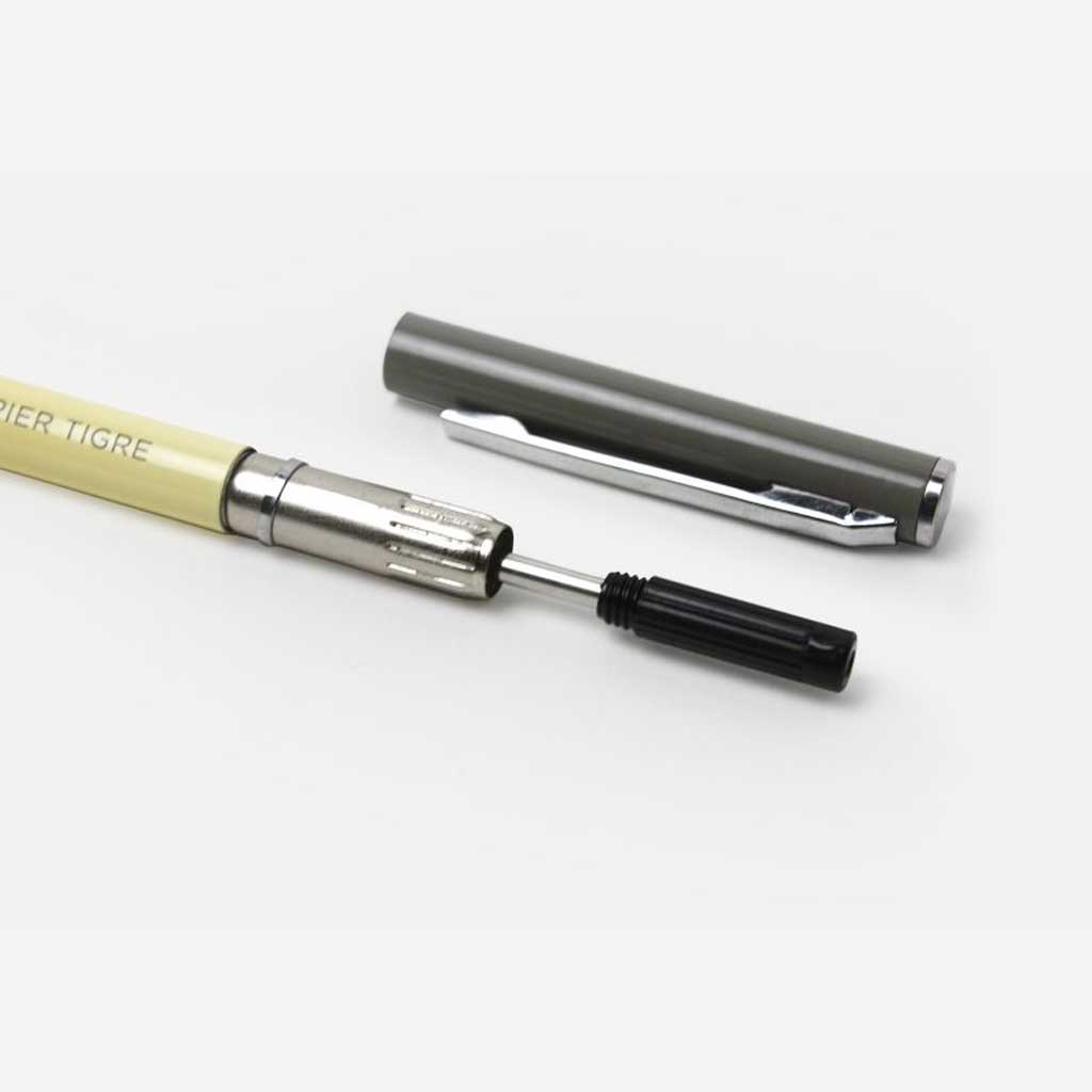 Black ink refill inserted into yellow pen on white surface