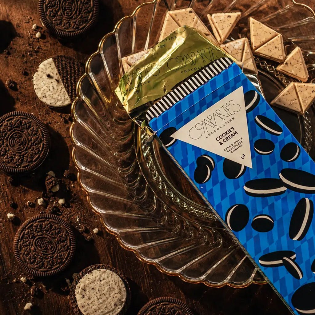 Open box of cookies & cream chocolate bar on platter, surrounded by sandwich cookies.