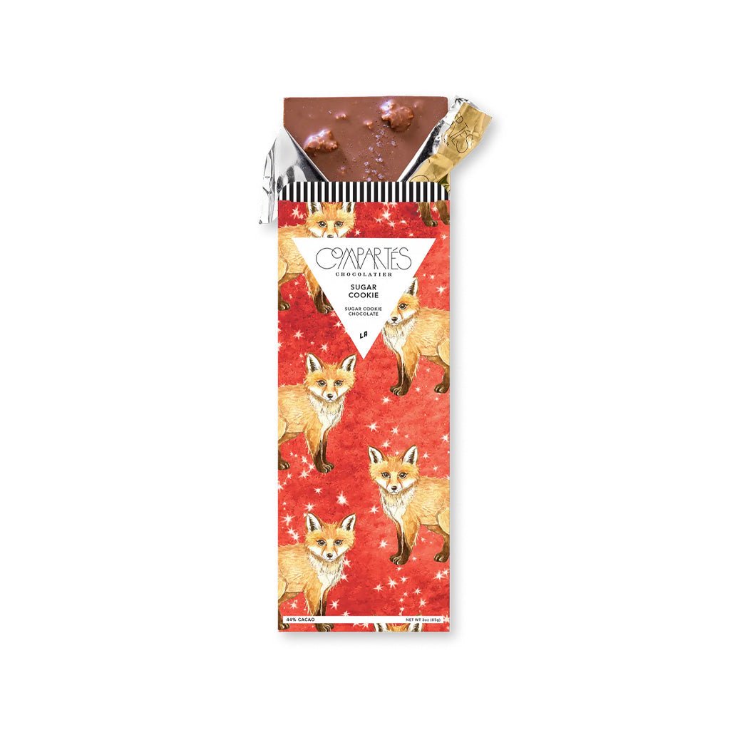 Sugar cookie chocolate bar in gold foil and red packaging with illustrated foxes.