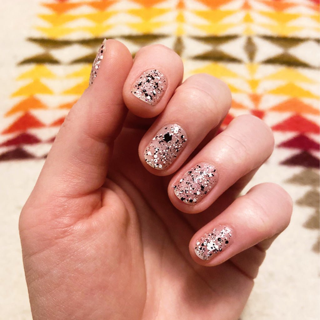 Hand wearing cookies and cream sheer glittery nail polish