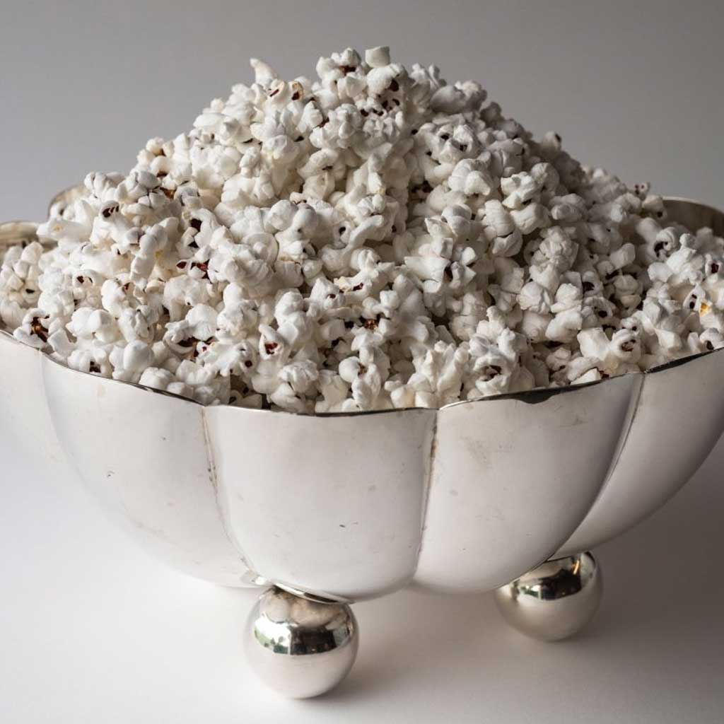 Silver bowl of popcorn on gray background