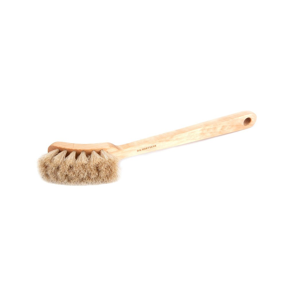 A wooden dish brush with light bristles on white background