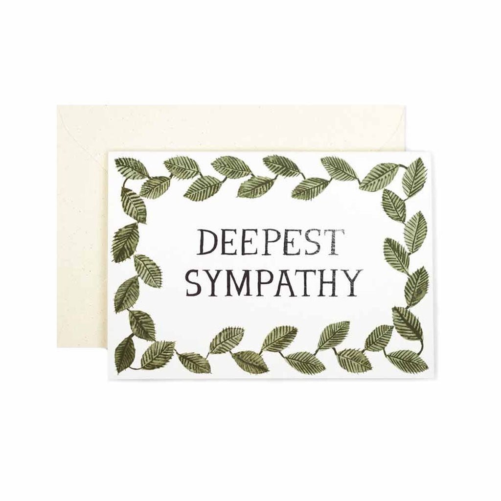 Greeting card with text “deepest sympathy” framed by a green leafy border, shown with a cream envelope.