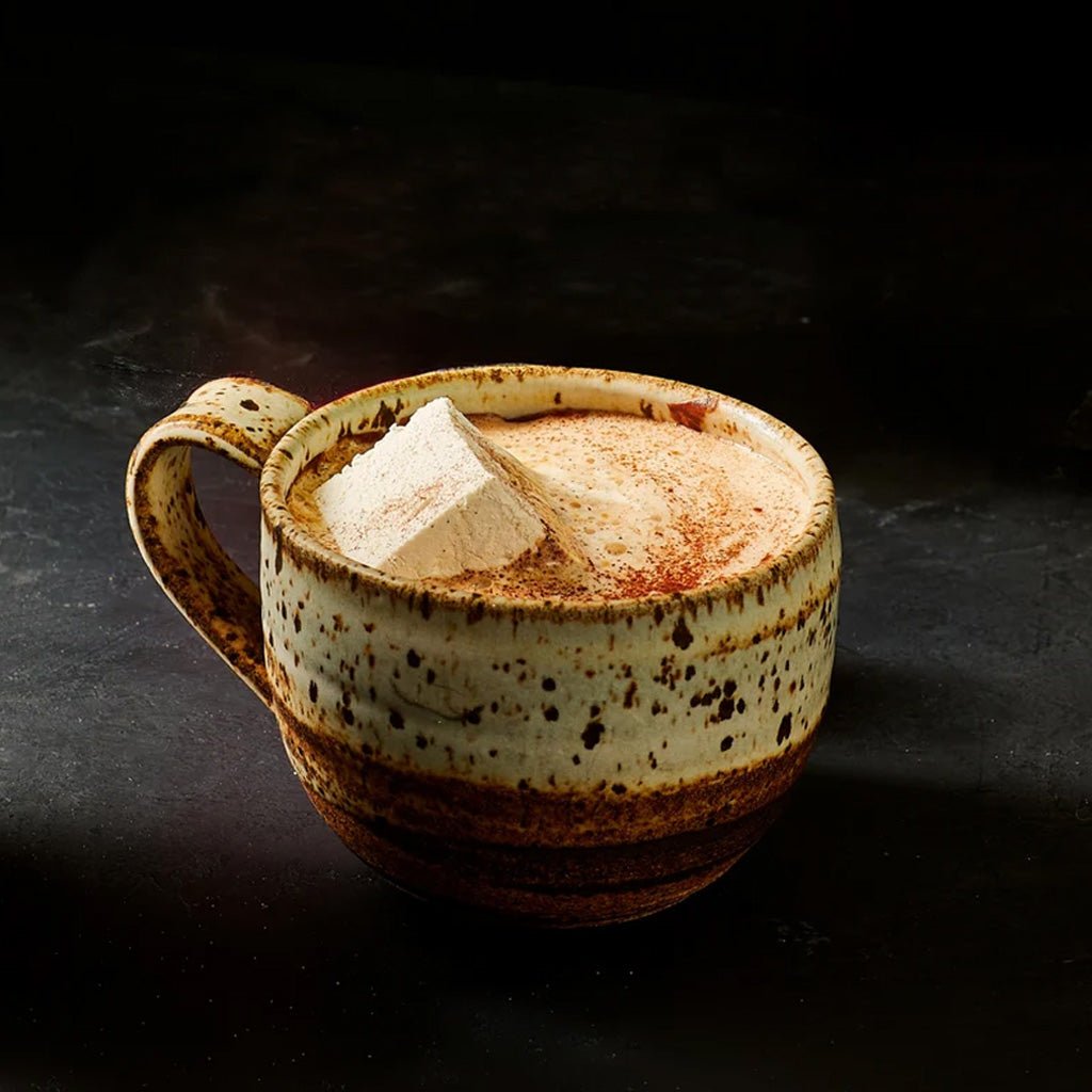Mug of hot cocoa with marshmallow on dark background.