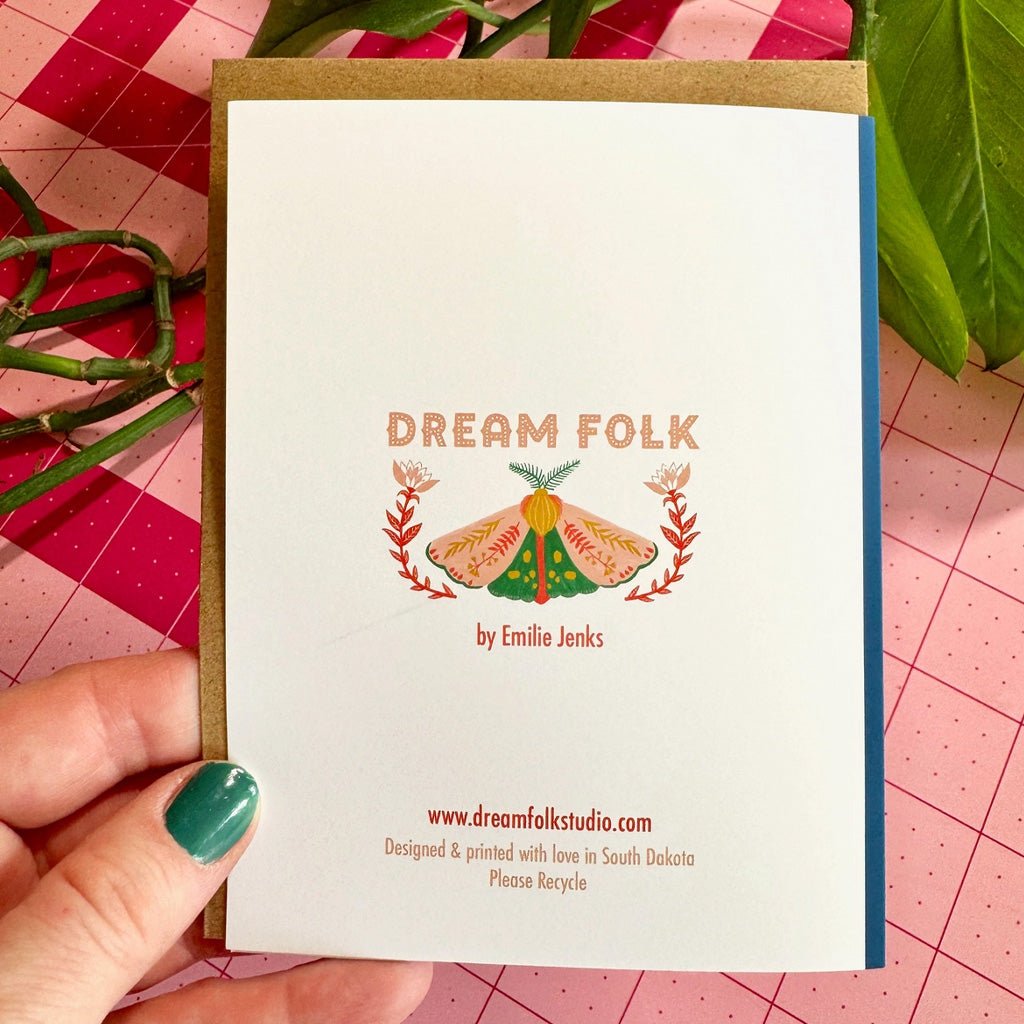 Hand holding card with Dream Folk Studio branding.