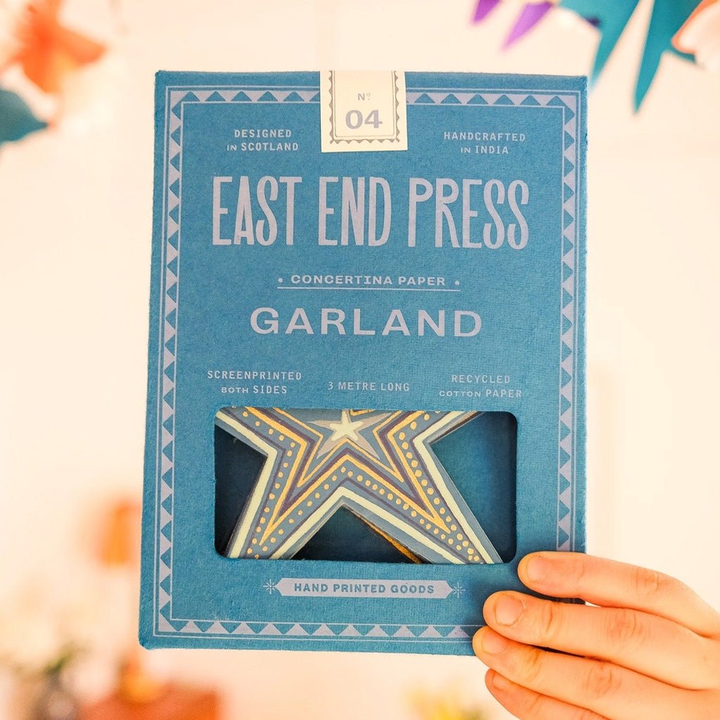 Hand holding blue box of star concertina garland.