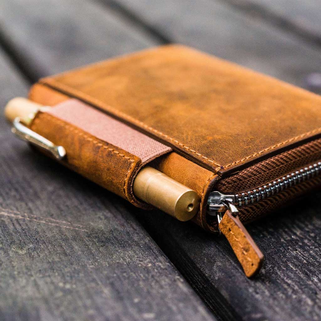 Brown leather wallet with a pen on a wooden surface