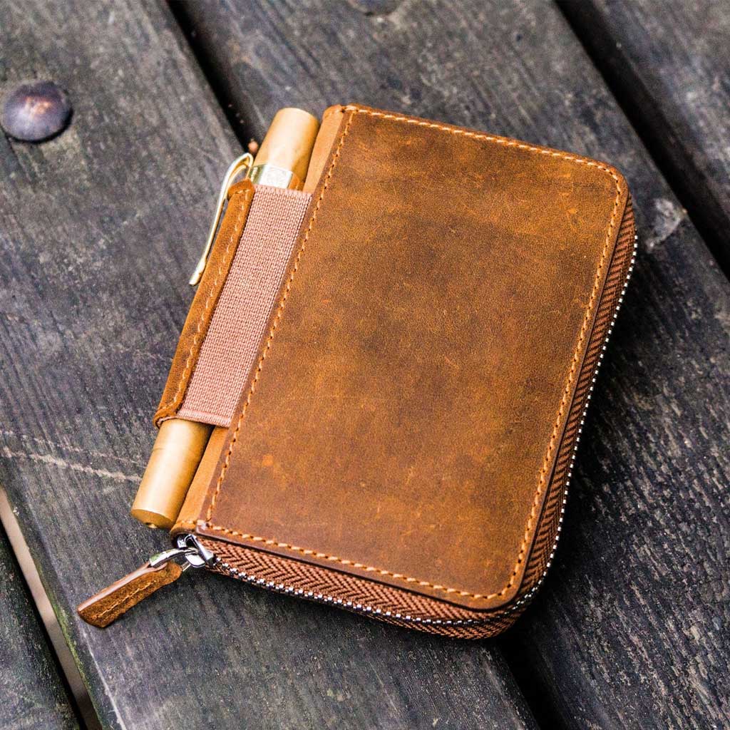 Brown leather wallet with a zipper on a wooden surface