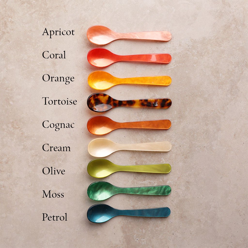 Row of colored egg spoons with labels on light background
