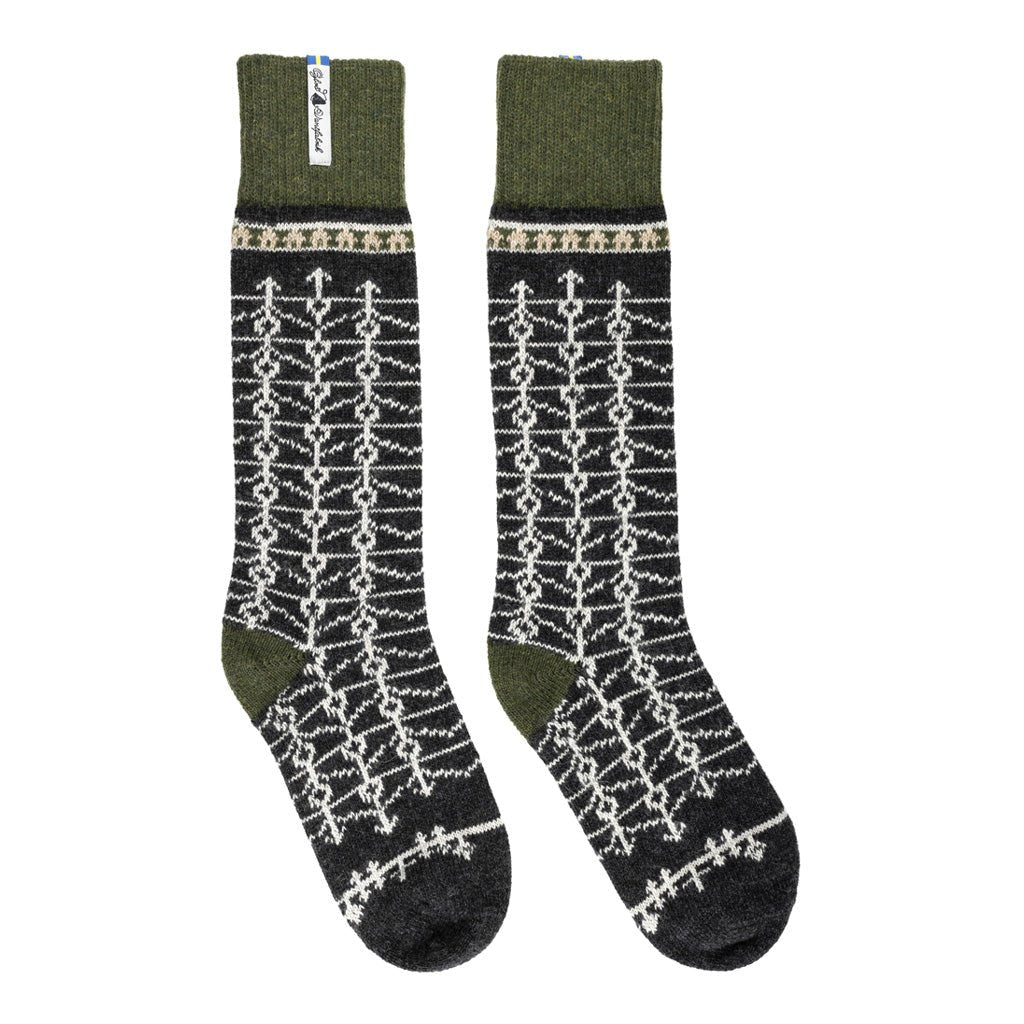 A pair of tall wool socks with a dark charcoal gray base, featuring a white geometric knit pattern and olive green cuffs and heels, displayed against a plain white background.
