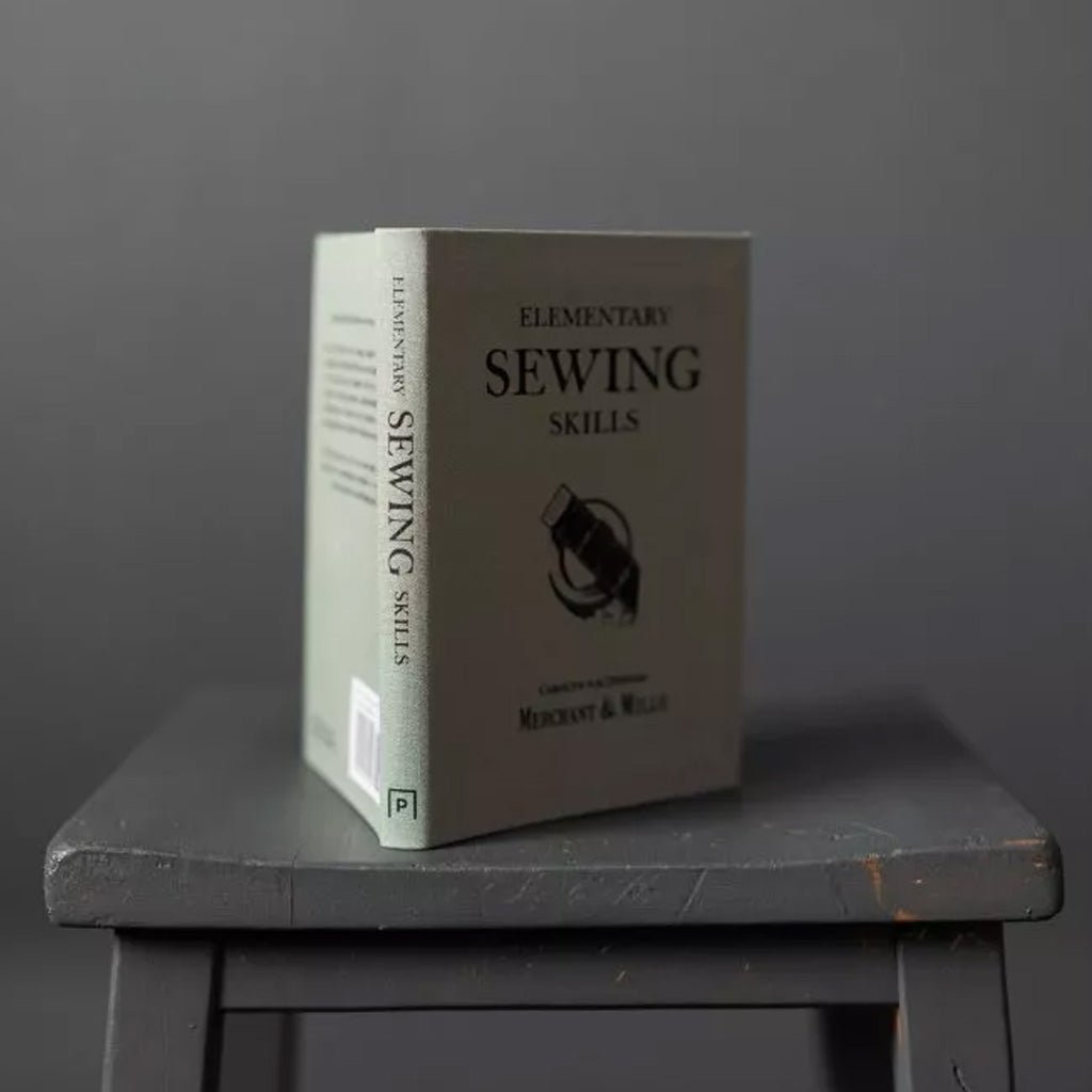 Merchant and Mills Elementary Sewing Skills Book on gray stool on gray background