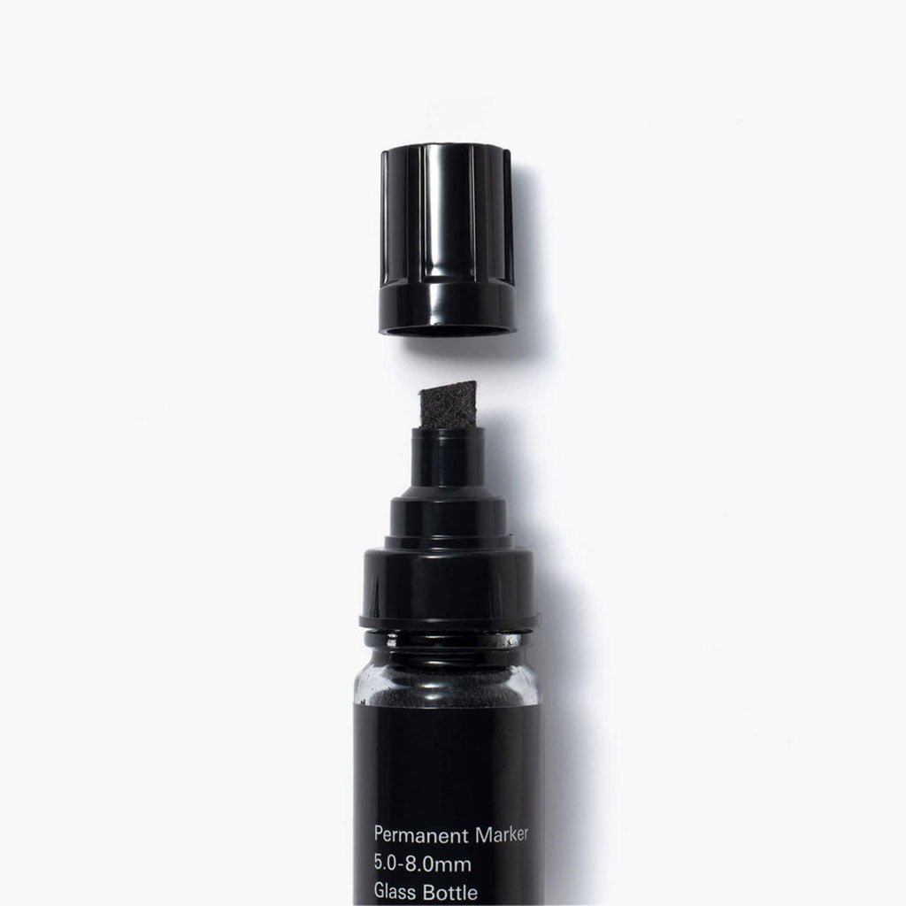 Chisel tip permanent marker with glass bottle on a white background