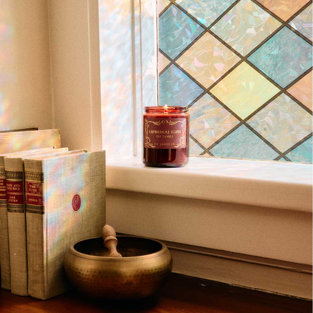 Candle on a windowsill with books and a singing bowl in the foreground