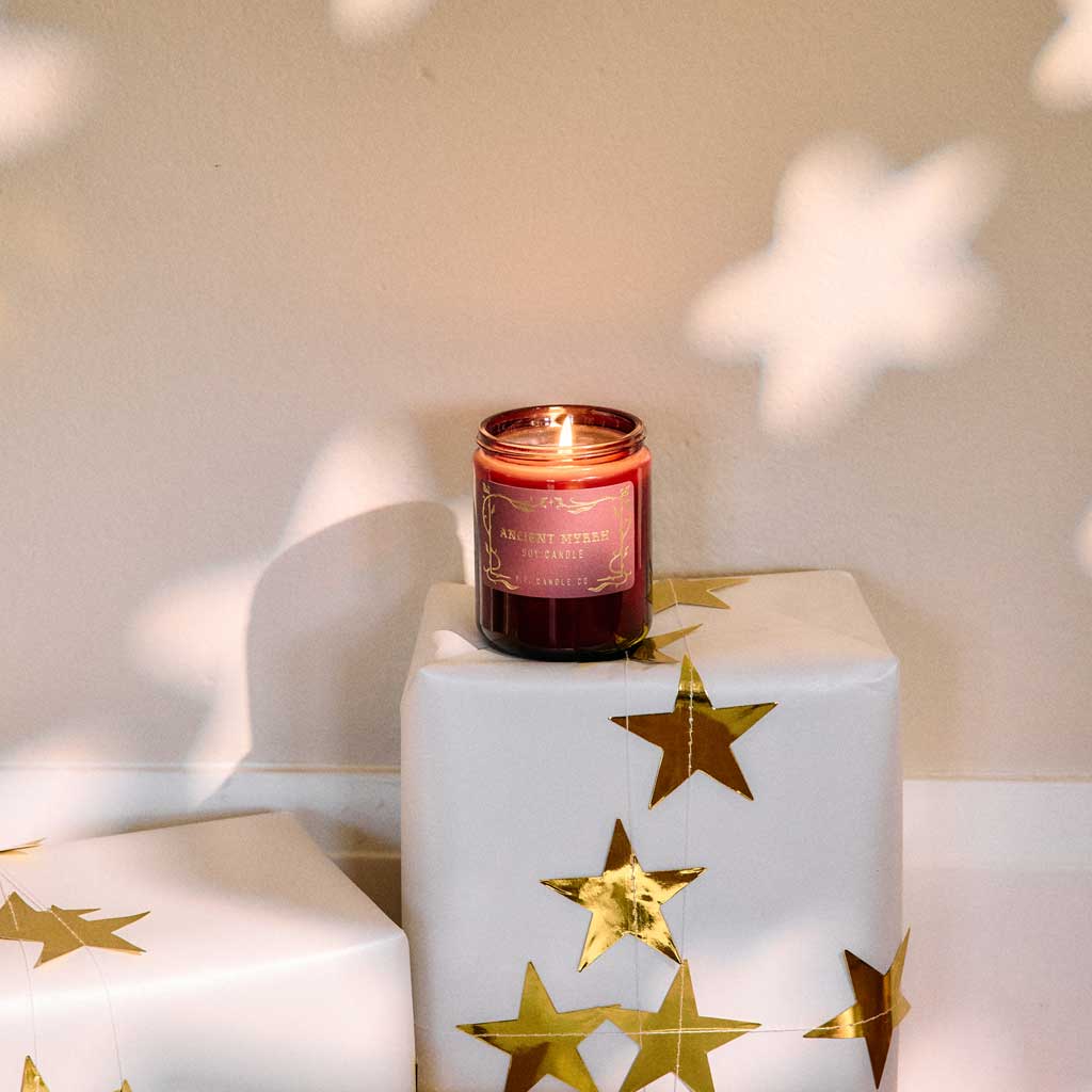 Candle on a white box with gold stars, soft lighting