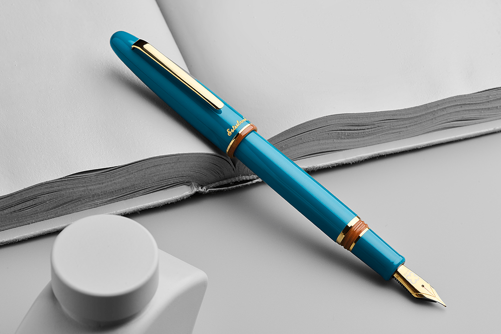 Blue fountain pen with gold accents on a light gray background