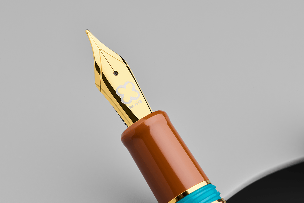 Close-up of a fountain pen with a gold nib and brown and blue body on a gray background
