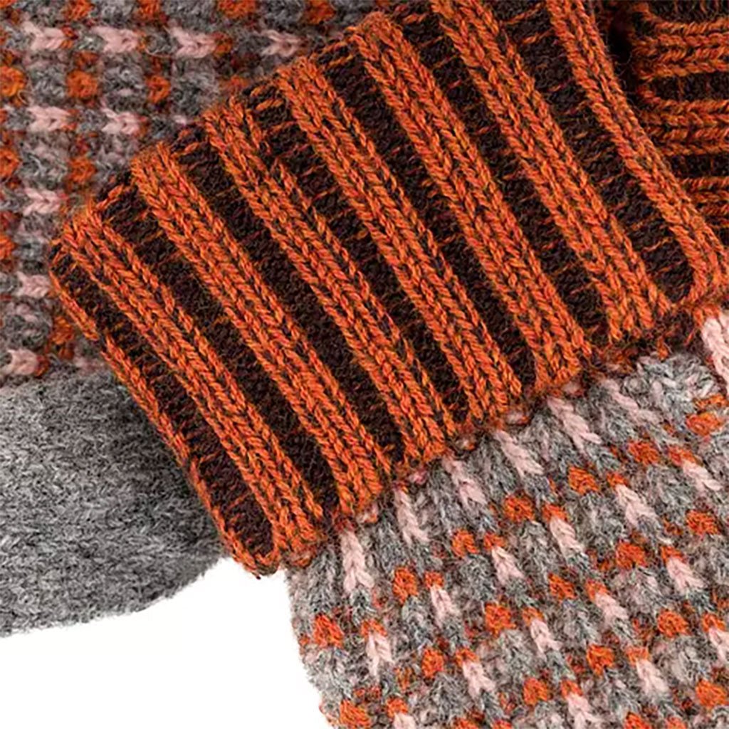 Close-up of a knitted fabric with orange and brown stripes on a checkered background.